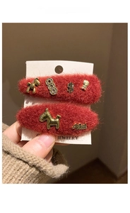 Detail of red plush hair clips with gold metal charms on a jewelry card being held