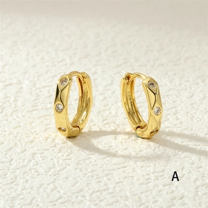 Close-up of gold huggie earrings featuring embedded zircons and a hinged clasp mechanism
