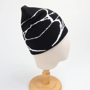 Detail shot of the white spider web jacquard pattern on a black knit beanie hat