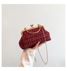 Detail of red tweed handbag with gold metal frame, lock and elegant chain shoulder strap
