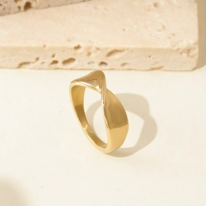 Minimalist gold titanium steel ring with twisted design on a neutral stone background