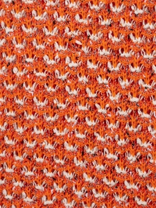 Macro texture of orange and white knitted fabric with detailed crochet weaving pattern