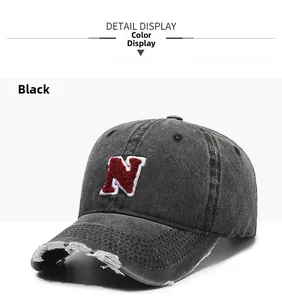 Detailed shot of distressed brim and red towel-embroidered N logo on black denim cap