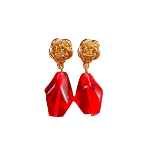 Elegant gold flower earrings with red faceted crystal pendants on a white background