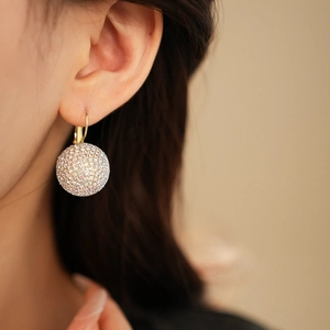Close-up of elegant gold spherical drop earring with pavé rhinestones on model