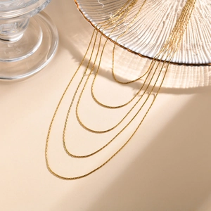 Élégant collier à plusieurs rangs en or 18 carats avec une texture fine sur fond beige chaud