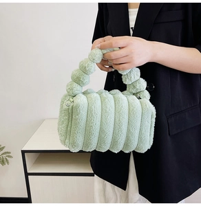 Detail view of light green faux fur handbag with textured cylindrical design and ball handle