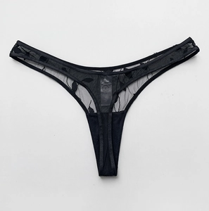 Macro shot of black mesh thong with delicate leaf embroidery and sheer lace textures