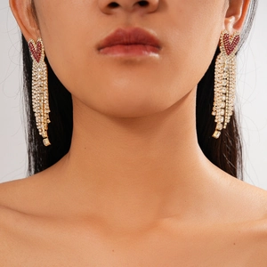 Detail of luxury heart tassel earrings with red rhinestones worn by a model