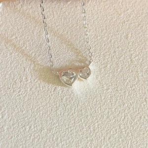 Macro view of double heart-shaped pendant necklace featuring clear cubic zirconia crystals
