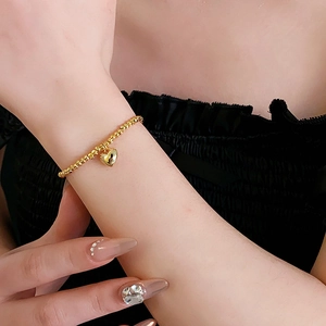 Close-up of elegant gold beaded heart bracelet worn on model wrist with minimalist style
