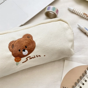 Close-up of canvas pencil case with cute brown bear embroidery and Smile text detail