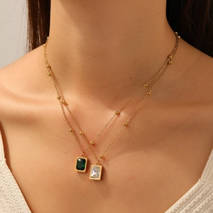 Detail showing double-layered gold chain with green and white cubic zirconia cube pendants