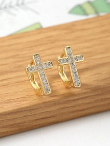 Close-up of golden cross hoop earrings with pavé cubic zirconia on wooden stand