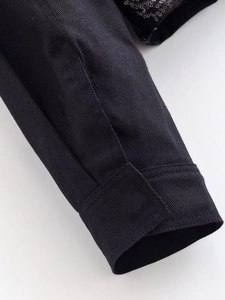 Close-up of black jacket cuff featuring twill fabric and shiny sequin patchwork detail
