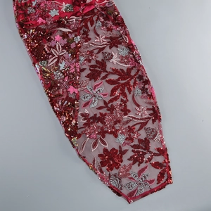 Close-up of red sequined embroidery on floral mesh fabric for formal dress