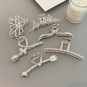 Close-up of elegant silver bow hair clips and heart-shaped metal claw clips set
