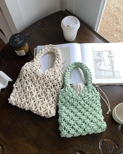 Detail of handmade woven bags in cream and mint green on a vintage wooden table