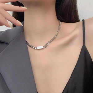 Close-up of silver stainless steel curb chain necklace with smooth oval metal plate on neck