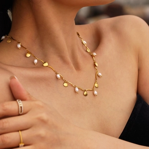 Gold shell necklace with freshwater pearls and stainless steel coins on model