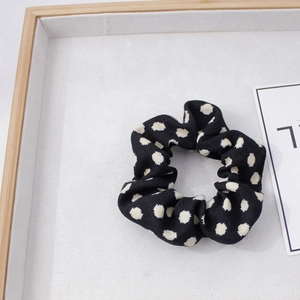 Détail d'un chouchou noir à pois blancs avec une texture de tissu épais et doux
