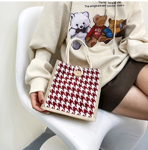 Detail of red houndstooth canvas tote bag with cotton rope handles and wooden button closure
