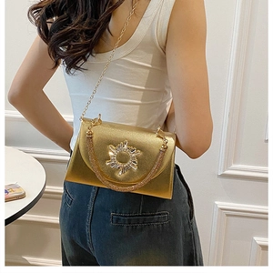Elegant gold chain bag with sunburst rhinestone detail worn by model in casual style