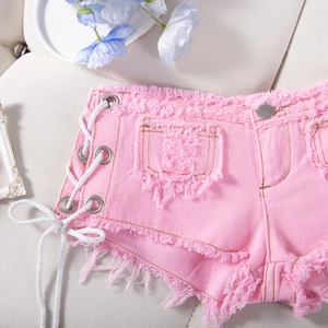 Dettaglio di pantaloncini di denim rosa con lacci laterali e orli sfrangiati