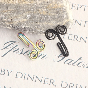 Macro detail of rainbow and black stainless steel fake nose rings on stone background