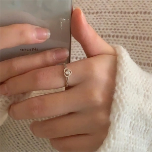 Close-up of S925 silver heart ring with twisted band and clear zircon on a hand