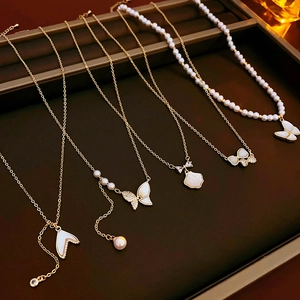 Vue détaillée des colliers plaqués or avec zircon, nacre et pendentifs papillon