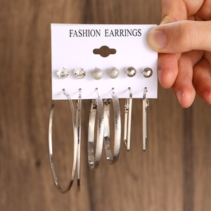Handheld detail of six-piece geometric earring set with silver hoops and pearls