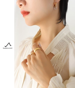 Detail view of interlocking gold and silver stainless steel earrings worn by a model