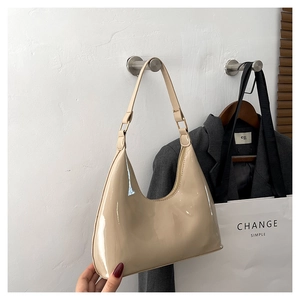 Detail of glossy beige patent leather hobo bag with gold buckle on crescent shape