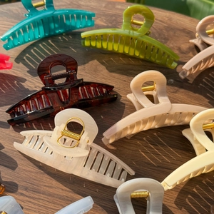Detail of 13.5cm butterfly hair claws in various solid colors on a wooden table