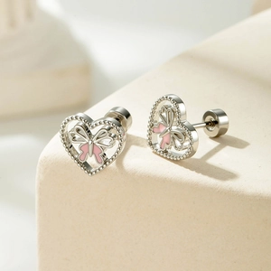 Silver heart stud earrings with pink butterfly and screw back on a neutral background