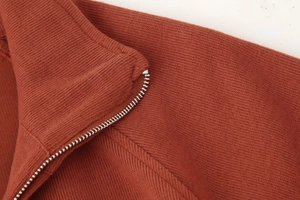 Detailansicht des Metallreißverschlusses und der Strickstruktur am rostroter Sweatshirts