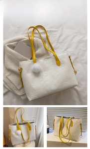 Close-up of white embossed tote bag featuring yellow straps and a fluffy pompom detail