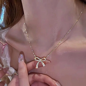 Elegant gold bow necklace with shimmering zircon stones worn on woman neck
