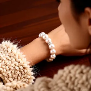 Elegant white pearl bracelet with zircon flower detail worn by model on cozy knit sweater