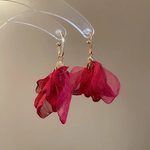 Detail of red chiffon flower earrings with golden metal hooks on transparent display stand