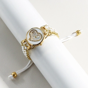 Detailed macro view of heart-patterned watch dial with white braided wristband