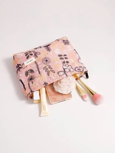 Pink floral embroidered makeup bag with flowers and makeup brushes in a stylish setup