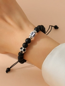 Detail of adjustable beaded bracelet with matte black beads and soccer-shaped silver charm