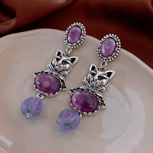 Macro detail of vintage style cat earrings with purple oval stones and silver accents
