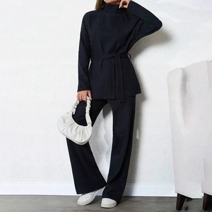 Detail of high neck long sleeve top with waist bow and ribbed knit wide leg trousers
