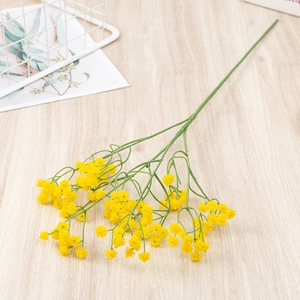 Detailed top view of realistic yellow gypsophila flower bouquet on light wood background