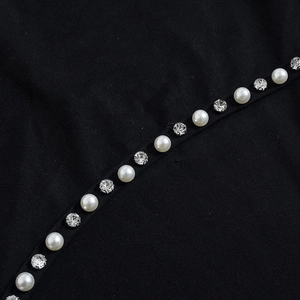 Détail des perles et strass scintillants sur l'ourlet de la robe noire