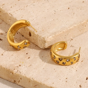 Detailed view of 18K gold plated C-shaped earrings with star zircons on beige stone