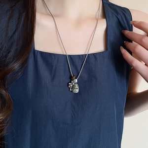 Detail of tiger eye and Dalmatian jasper pendant necklace on a blue neckline